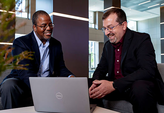 Two coworkers talking in front of laptop